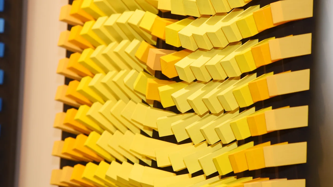 Man sieht eine Plastik auf vielen gelben Würfeln.